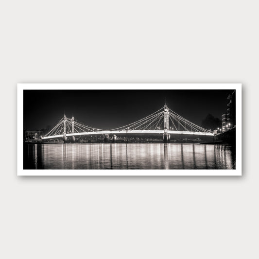 A photographic print of Albert Bridge by Night, framed with a white border and shown against a light gray background.
