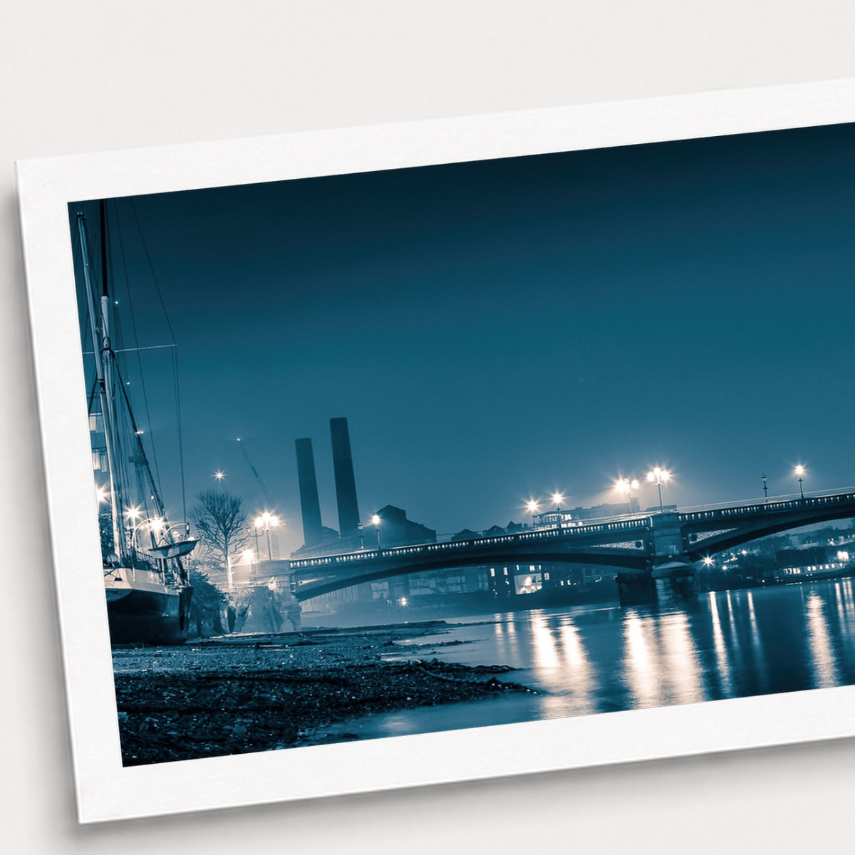 A photographic print of Battersea Bridge, shown with a white border and angled presentation on a light background.