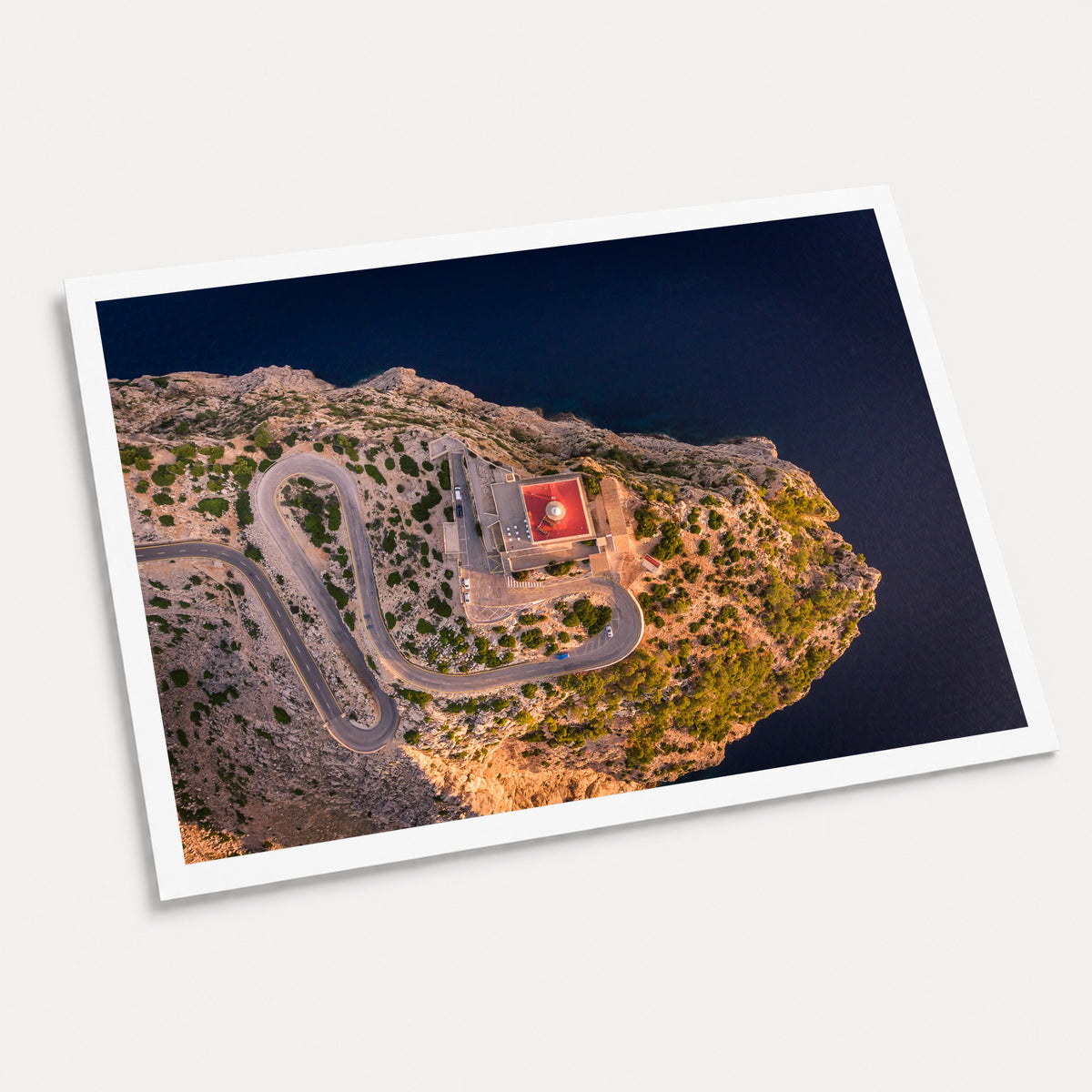 A photographic art print of Cap De Formentor Lighthouse from above, displayed at an angle on a light gray background.