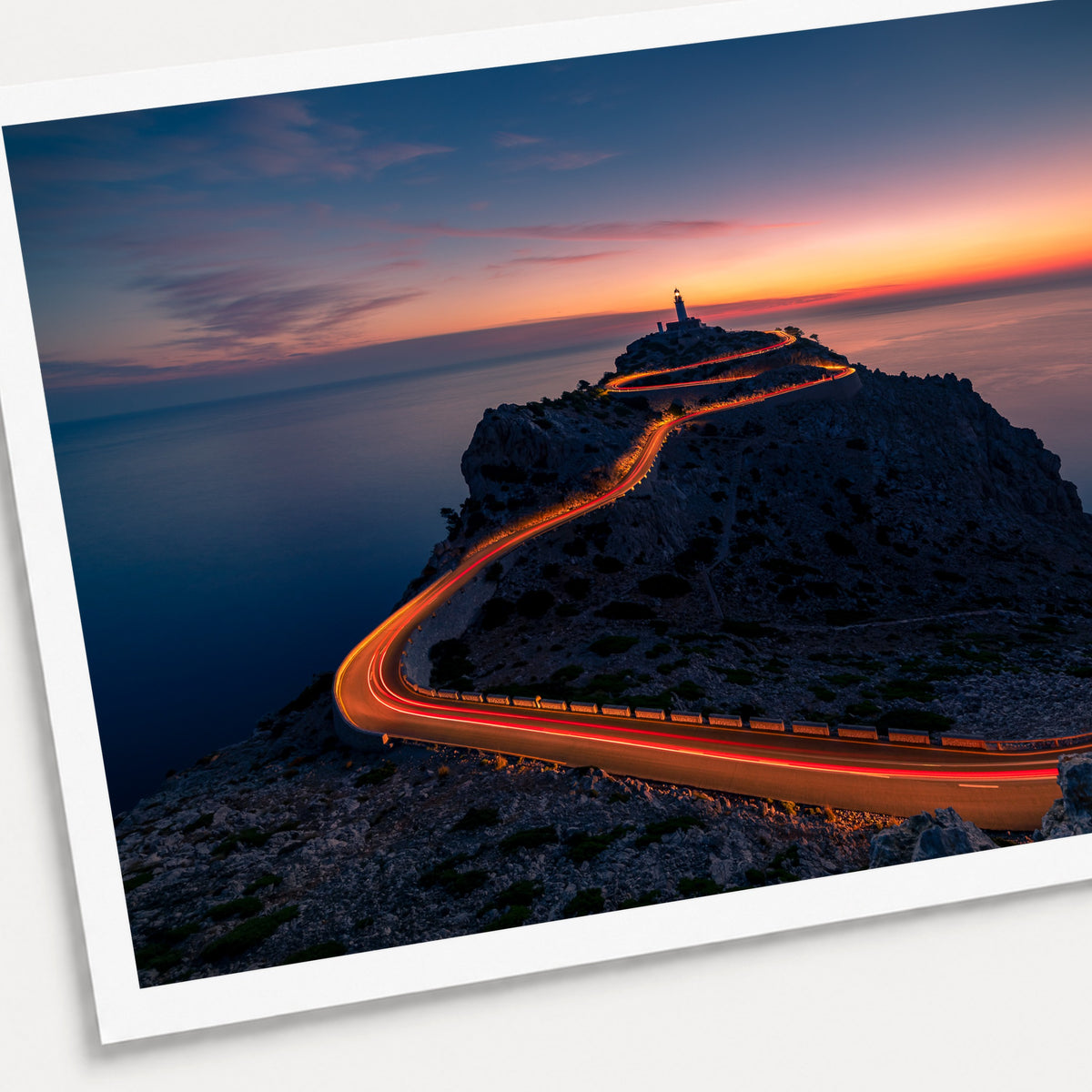A photographic print of Cap De Formentor Lighthouse, shown with a white border and angled presentation on a light background.