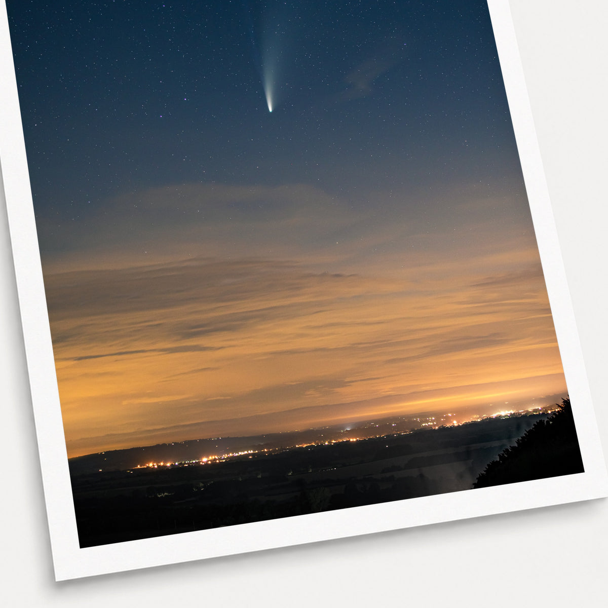 A photographic print of Comet Neowise, shown with a white border and angled presentation on a light background.