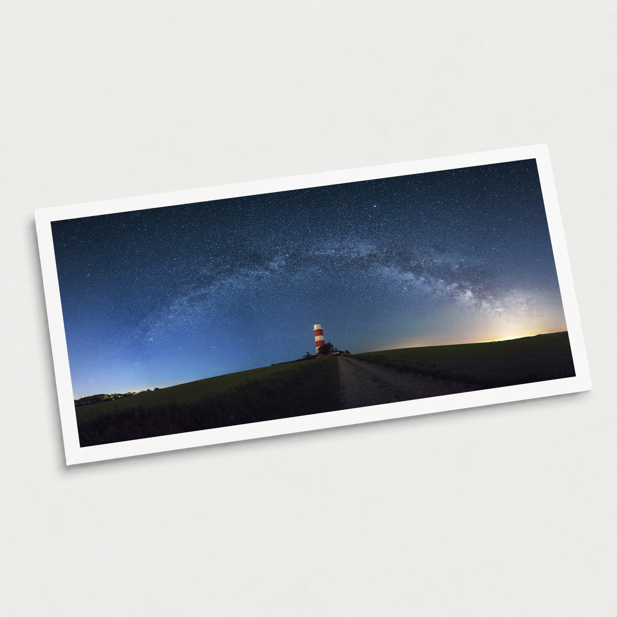 A photographic art print of Happisburgh Lighthouse Milky Way, displayed at an angle on a light gray background.