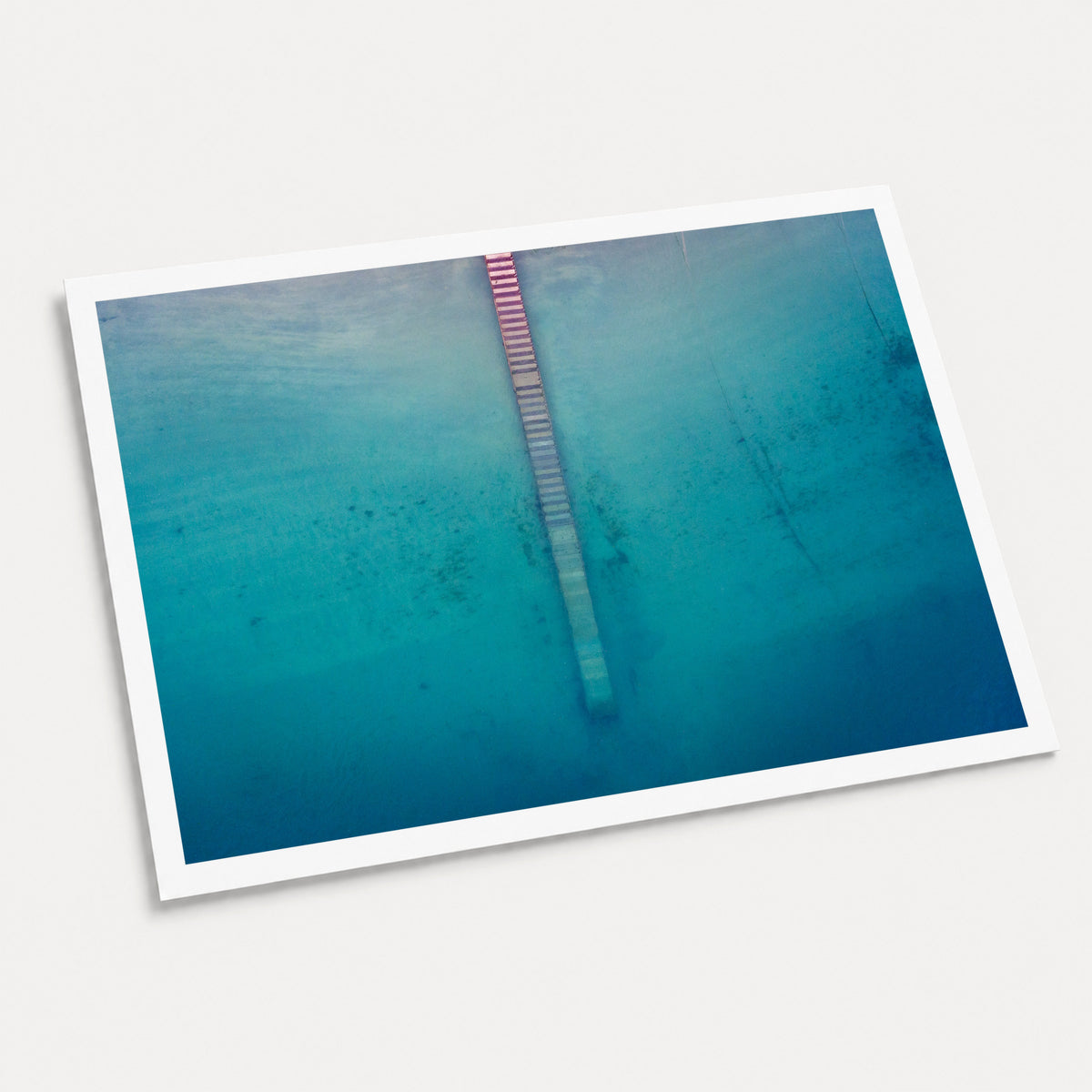 A photographic art print of Jetty from Above, displayed at an angle on a light gray background.