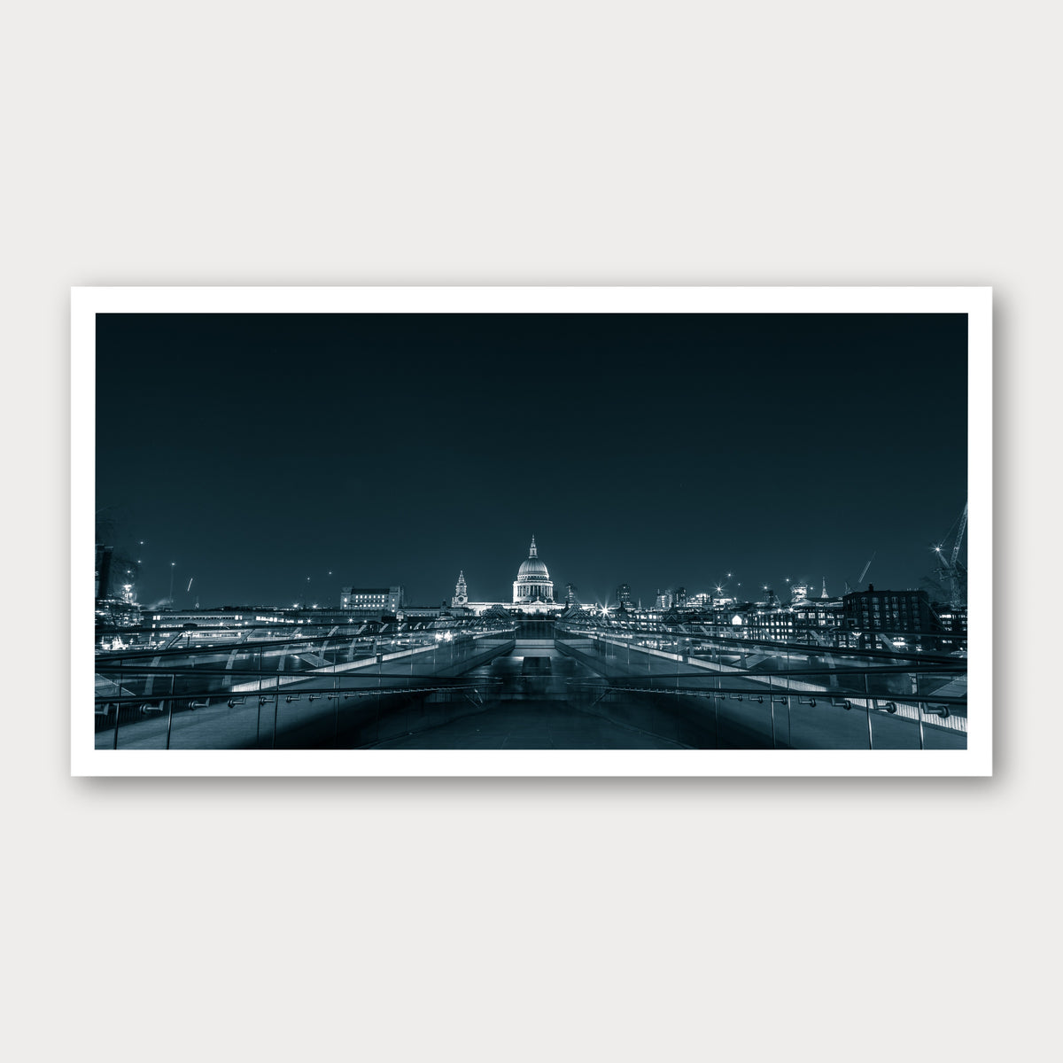 A black and white photographic print of Millennium Bridge, framed with a white border and shown against a light gray background.
