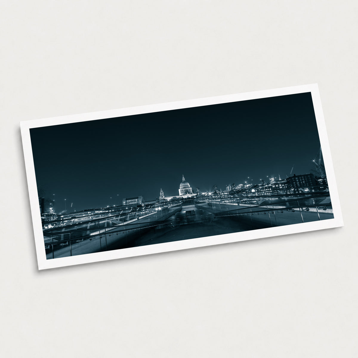 A black and white photographic art print of Millennium Bridge, displayed at an angle on a light gray background.