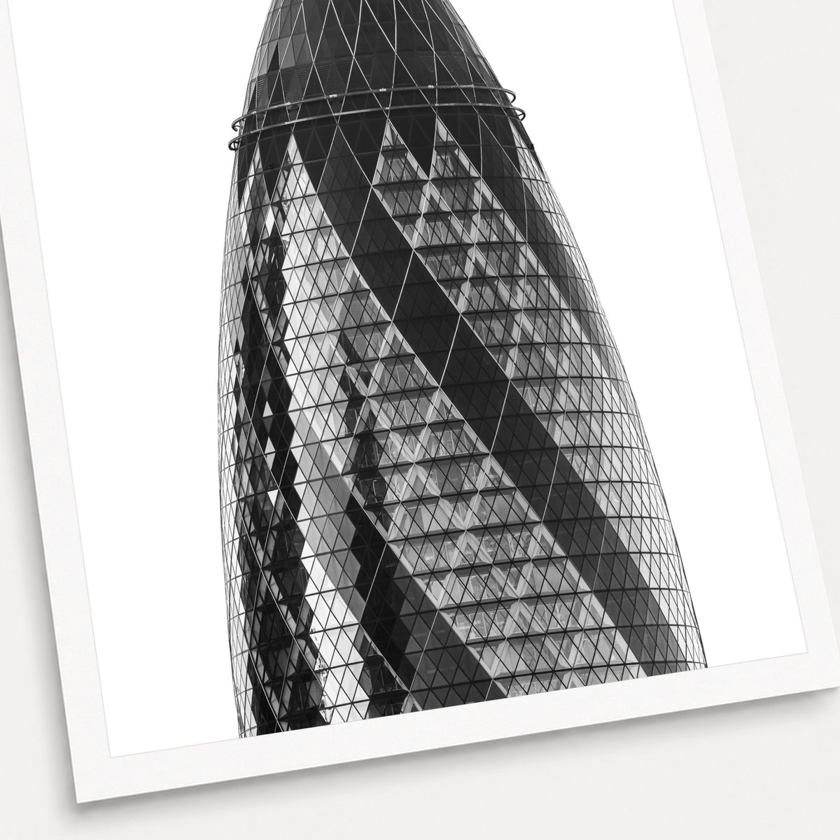 A black and white photographic print of The Gherkin, shown with a white border and angled presentation on a light background.