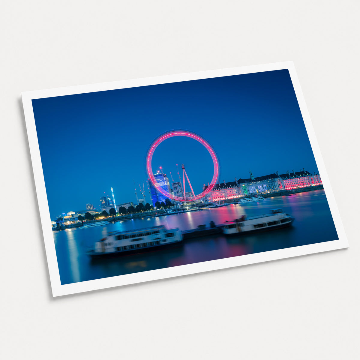 A photographic art print of The London Eye, displayed at an angle on a light gray background.
