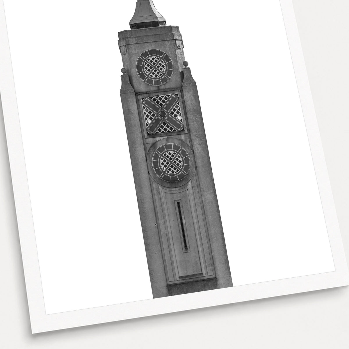 A black and white photographic print of The Oxo Tower, shown with a white border and angled presentation on a light background.