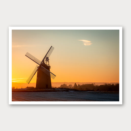 A photographic print of Windmill Sunrise, framed with a white border and shown against a light gray background.