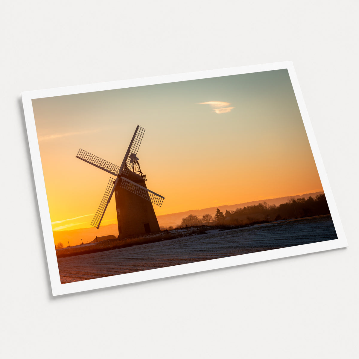 A photographic art print of Windmill Sunrise, displayed at an angle on a light gray background.